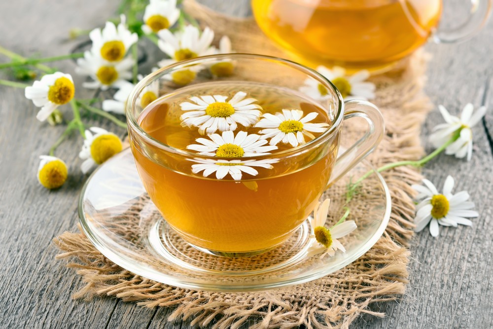 Herbal chamomile tea in glass cup on wooden table