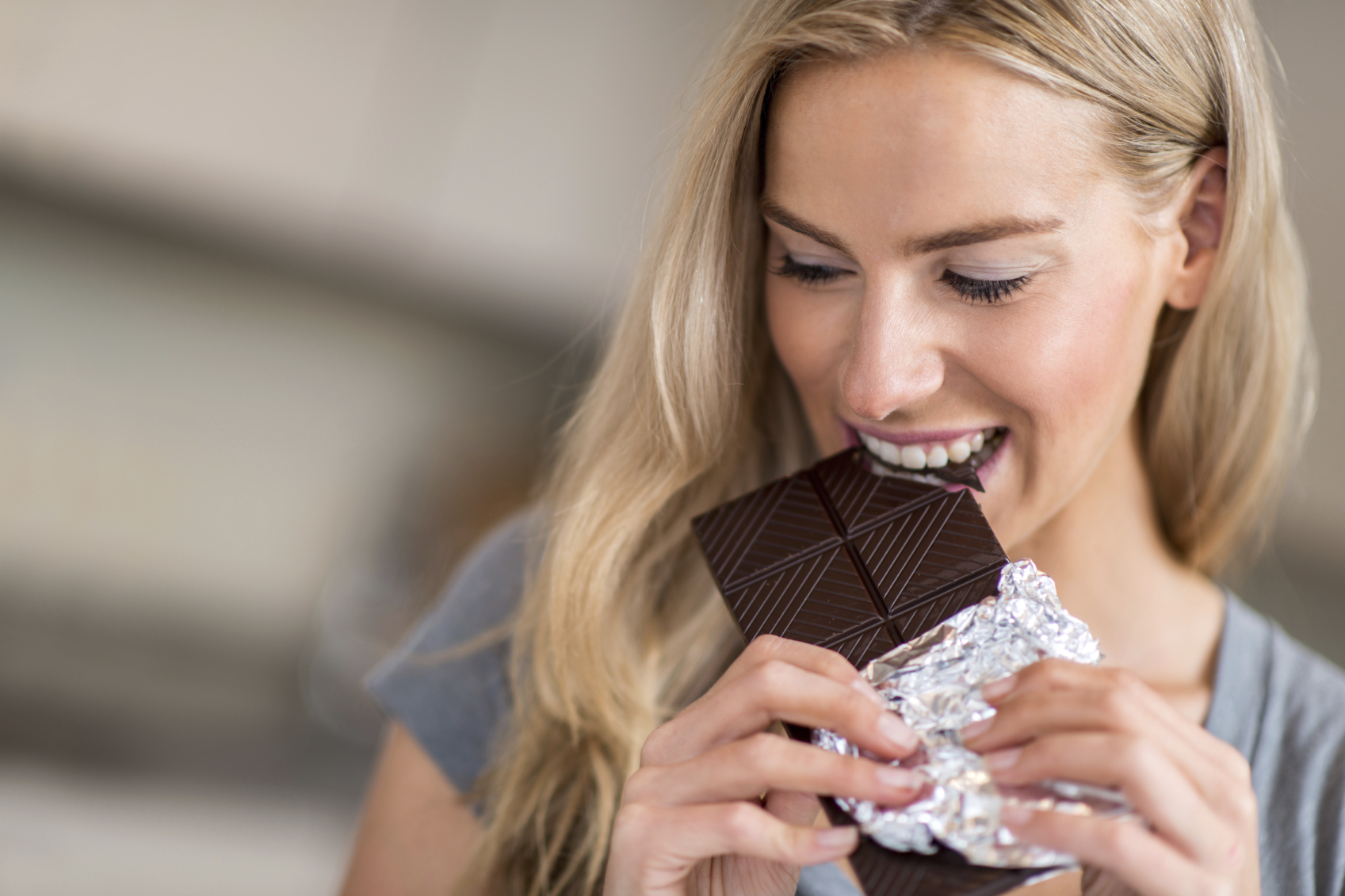 Happy woman biting a chocolate bar