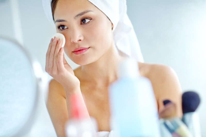 An attactive young Asian woman applying moisturizer with a towel on her head