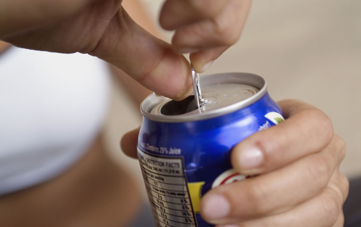 Extreme close-up of woman opening canned drink, focus on foreground