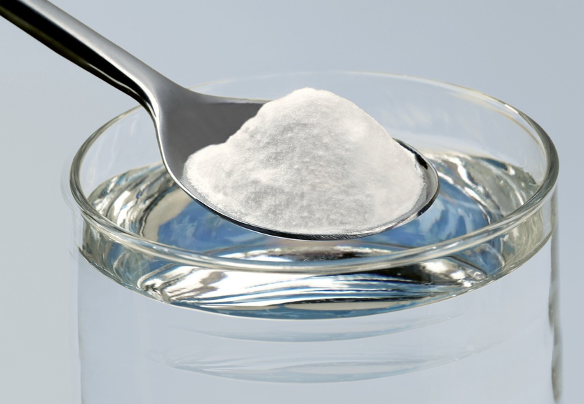 Spoon of baking soda above a glass of water