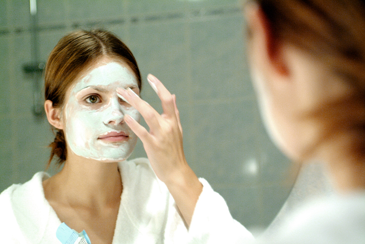 Close-up of a young woman applying a facial mask