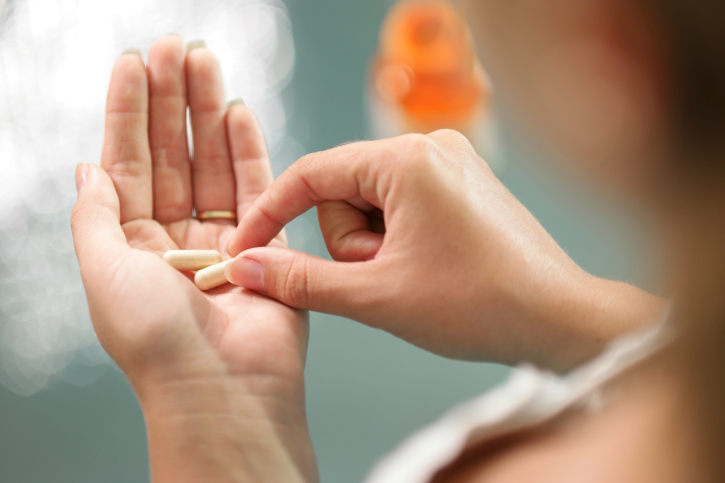 Young woman taking vitamins ginseng pill